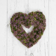 a heart - shaped wreath made out of moss sits on a white painted wood background