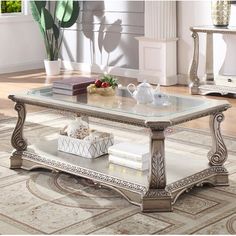 a coffee table sitting on top of a rug next to a vase and potted plant