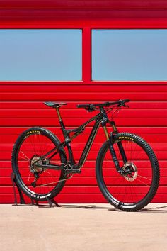 a mountain bike parked in front of a red wall