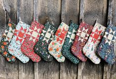 christmas stockings lined up against a wooden fence with snowflakes and stars on them