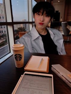 a woman sitting at a table in front of a tablet computer and a cup of coffee