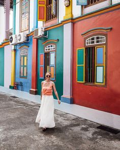 a woman is walking in front of colorful buildings