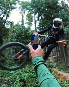 a person on a mountain bike doing tricks in the air while holding onto another person's hand