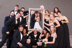 a group of people in formal wear posing for a photo with a framed picture frame