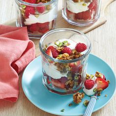 three desserts with strawberries, yogurt and granola on a blue plate