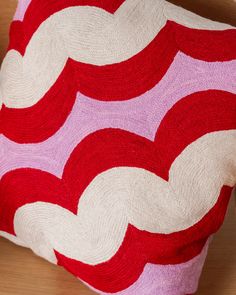 a red and white pillow sitting on top of a wooden table