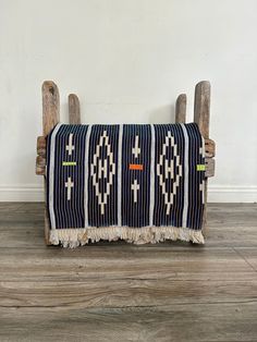 an old wooden bench with a blue and white blanket on it