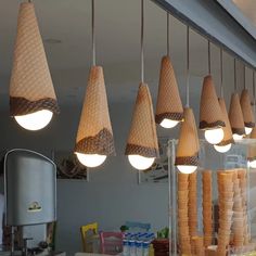 several cones hanging from the ceiling in a restaurant with lights above them and food on the counter