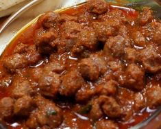 a bowl filled with meat and sauce on top of a table