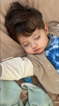 a young boy sleeping on top of a bed