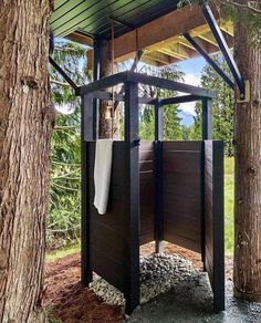 an outdoor shower in the middle of a tree lined area with rocks and gravel on the ground