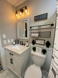 a white toilet sitting next to a sink in a bathroom under a mirror and lights