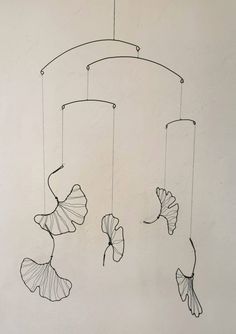 a drawing of three fish hanging from a string on the wall next to a white wall