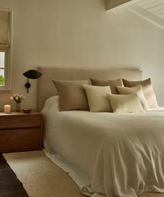 a bed with white sheets and pillows in a bedroom