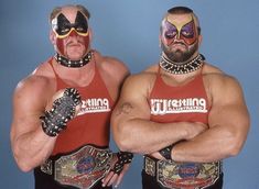 two men in wrestling gear standing next to each other with their hands on their hips