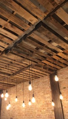 the lights are hanging from the wooden beam in the room with exposed brick walls and beams