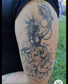 a woman's arm with an octopus tattoo on it, sitting in the grass