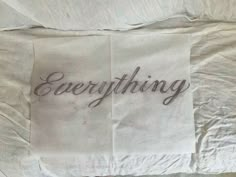 an unmade bed with the word everything written on it in cursive writing