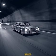 a black and white photo of a car driving through a tunnel