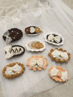 several crocheted hair clips are arranged on a white cloth covered table with lace