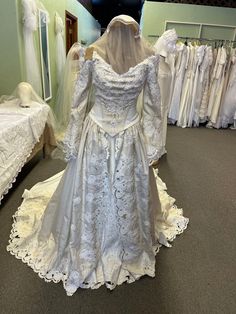 a white wedding dress is on display in a room full of other dresses and gowns