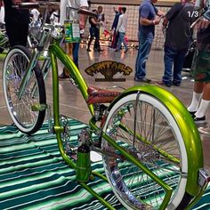 a green bicycle parked on top of a metal floor next to other people standing around