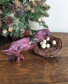 a pink bird sitting on top of a wooden table next to a nest filled with eggs