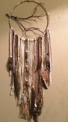 a dream catcher hanging on the wall next to a tree branch with feathers and beads