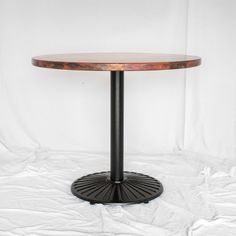 a round wooden table sitting on top of a white sheet