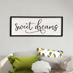 a bed with pillows and a framed sign on the wall above it that says sweet dreams