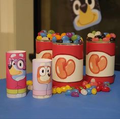 some colorful candy containers sitting on a blue table next to a cartoon character sticker