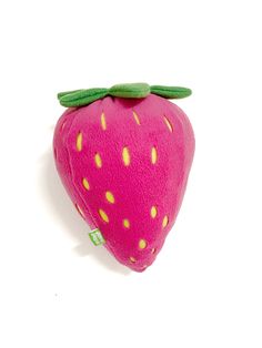 a pink stuffed strawberry with green leaves on it's back and yellow dots on the side