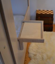 a bed with a tray on top of it next to a white rug and wooden dresser