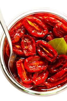 a spoon in a glass bowl filled with red peppers