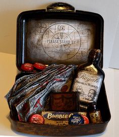 an open suitcase filled with different types of liquor and other items on top of a table