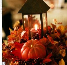 a candle is lit in front of some pumpkins and leaves