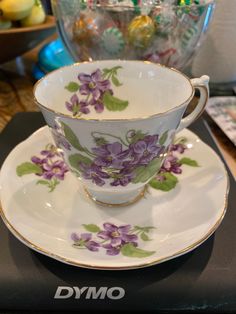 a tea cup and saucer decorated with purple flowers