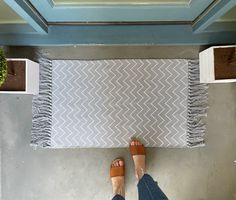 a person standing in front of a rug on the floor with their feet propped up