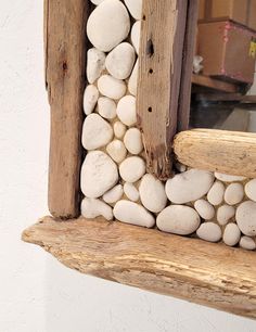 a wooden window frame made out of rocks and wood with a mirror in the background