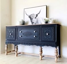 an ornately decorated sideboard stands in front of a painting and potted plants