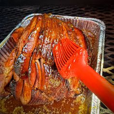 a large roasting pan filled with meat and gravy next to a spatula