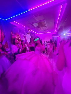 a group of people dancing in a room with purple lighting and decorations on the walls