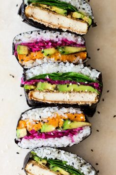 several sushi rolls are stacked on top of each other with rice and avocado