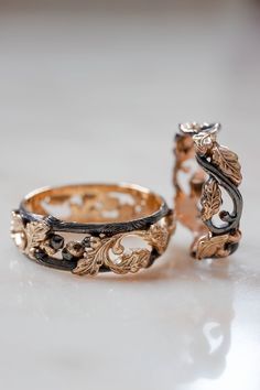 two wedding rings sitting next to each other on a white counter top, one with an intricate design