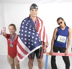 three people in swimsuits holding an american flag