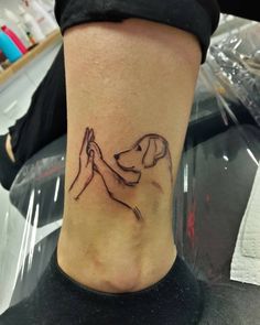 a woman's foot with a tattoo on it that has a dog and hands holding each other