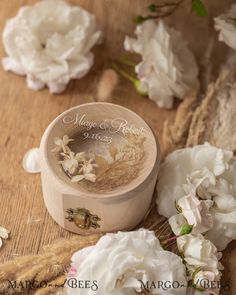 some white flowers on a wooden table and one is next to a small box with the word marry & robert written on it