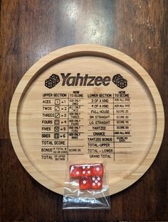 two red dices sitting on top of a wooden board with the words yahtze