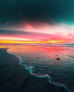 an ocean beach with waves coming in to shore and the sky filled with stars above