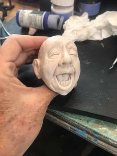 a person is making a face out of clay on a table with paint and glue